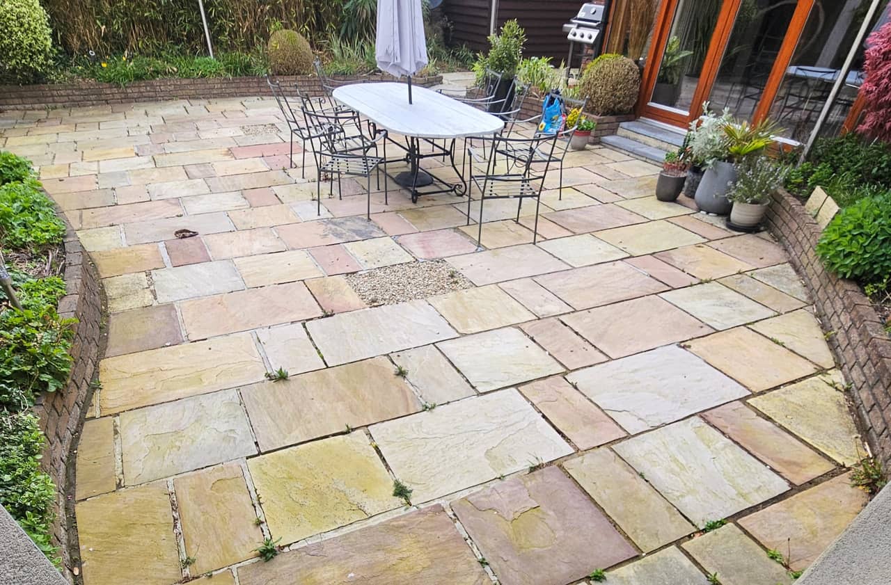 Indian sandstone patio before cleaning, weeds in the joints, dulled stone